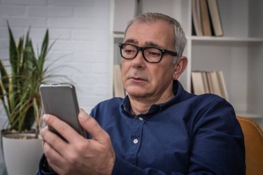 adult man with presbyopia or tired eyes consulting the phone at home