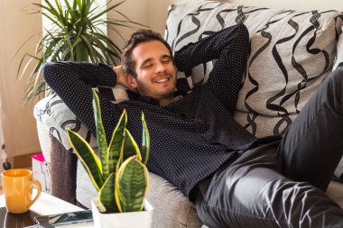 Rahat genç adam kanepede yatıyor.