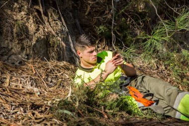 Orman işçisi ya da oduncu dinleniyor ve telefonu kullanıyor.