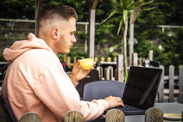 young man on the terrace of an outdoor bar using the laptop