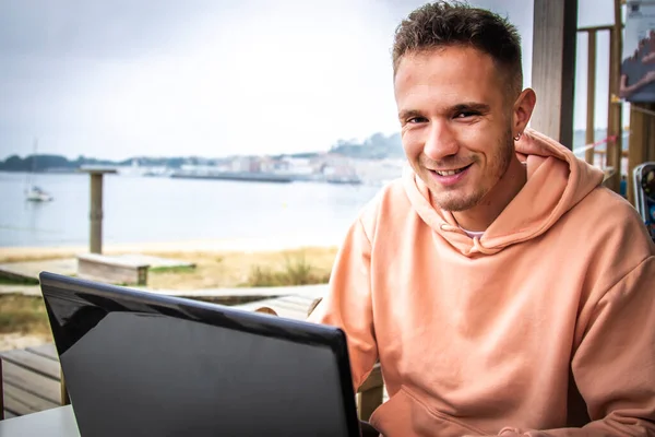 young man on the terrace of an outdoor bar using the laptop