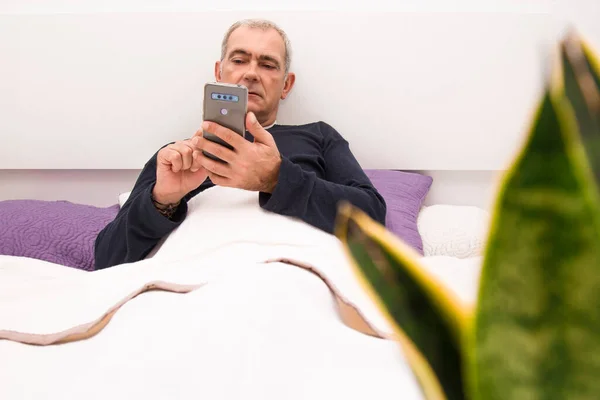 man chatting or sending message with phone in bed