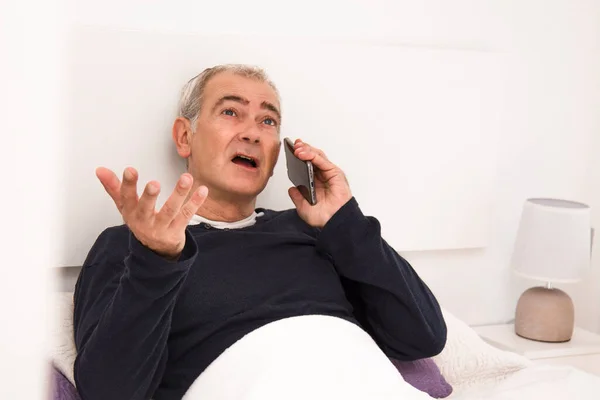 Άνθρωπος Στο Κρεβάτι Μιλάει Στο Κινητό Στο Κινητό Τηλέφωνο — Φωτογραφία Αρχείου