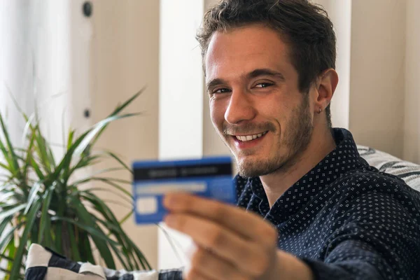 attractive young man with credit card at home