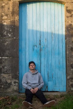 portrait of young man sitting with blue door background
