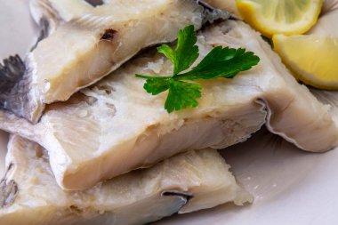 Tabakta maydanoz ve limon ile taze morina balığı.