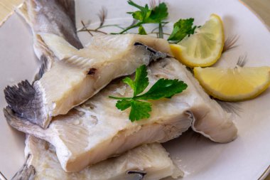 fresh cod with parsley and lemon on the plate