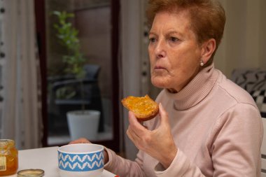 Son sınıf öğrencisi, kahvaltıda tost ve reçelli süt yiyor.