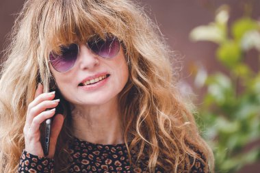 Gülümseyen yetişkin kadın cep telefonu kullanıyor