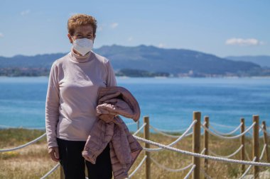 senior woman with mask on her face outdoors
