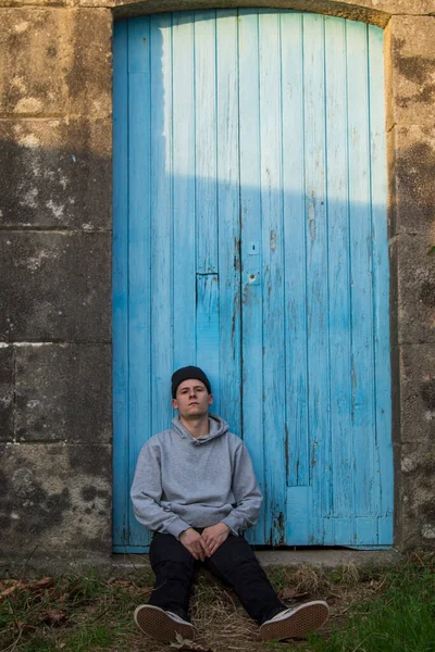 Portrait Young Man Sitting Blue Door Background — Φωτογραφία Αρχείου