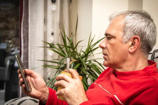 stock image relaxed adult man using smartphone and drinking coffee on sofa at home