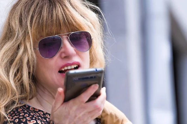 adult woman sending audio or voice message on the phone in the city