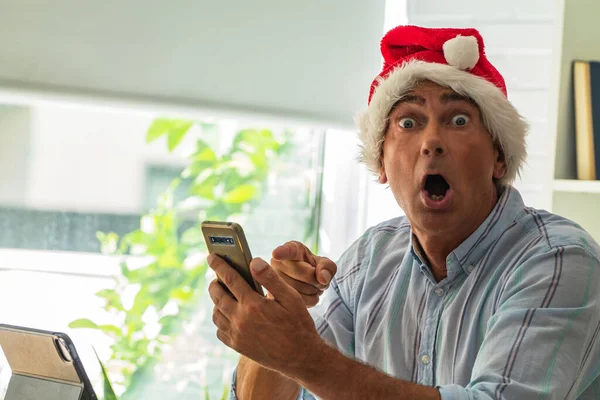 Άνθρωπος Καπέλο Σάντα Κατάπληκτος Χειρονομία Έκπληξη Κοιτάζοντας Κινητό Τηλέφωνο Χριστούγεννα — Φωτογραφία Αρχείου
