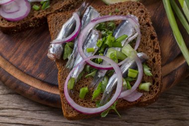 Karadeniz kıymalı, soğanlı ve maydanozlu siyah ekmek sandviçleri. Tahta bir tahta.