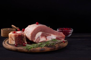 Kemiğin üzerinde birkaç parça çiğ et ve koyu ahşap arka planda kızılcıklar var.