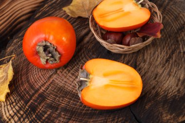 Taze portakallı hurma ağaçları ahşap masada sonbahar yapraklarıyla..