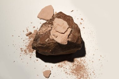 Yüz pudrası. Kırık kozmetik tozları sert gölgeli doğal bir taşın üzerinde. Kozmetik leke.