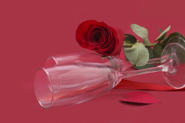 Sevgililer Günü geçmişi. İki bardak ve kırmızı arka planda zarif bir gül. Sevgililer Günü konsepti