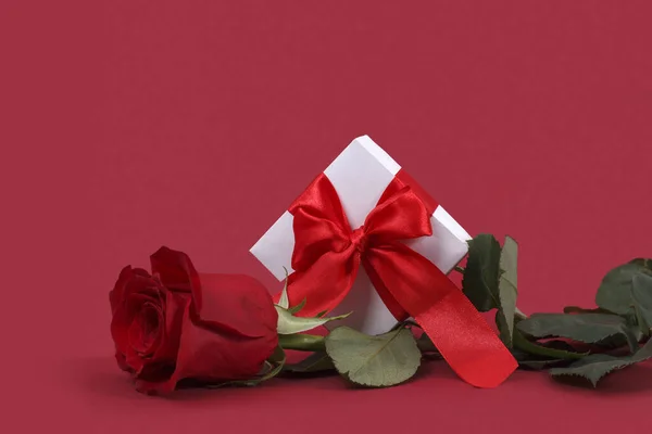 情人节的背景 红弓礼盒 红色背景上有一朵优雅的玫瑰 情人节的概念 — 图库照片