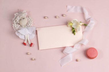 Davetiye ya da tebrik kartı modeli zarf, frezya çiçeği ve yumuşak pembe arka planda kurabiye. Markalaşma ve reklam şablonu