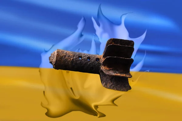 A mortar shell against the background of the Ukrainian yellow-blue flag on fire. The concept of peace and war.