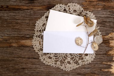Boş dikdörtgen bir kağıt ve ahşap bir arka planda örülmüş bir peçetenin üzerinde bir zarf. Markalaşma ve reklam şablonu