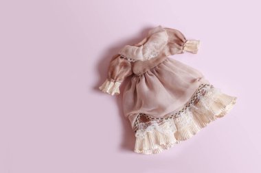 Pembe arka plandaki oyuncak bebek için fırfırlı güzel bir klasik elbise..