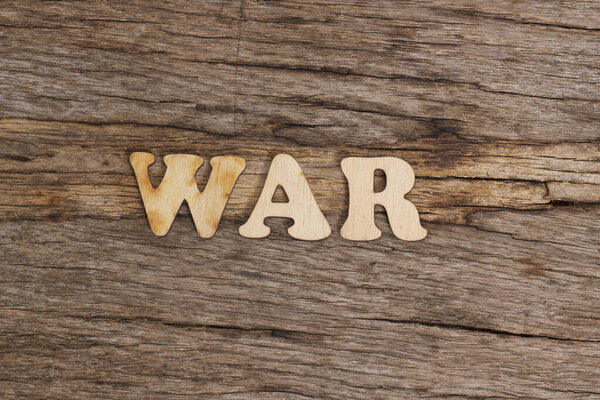 Wooden letters folded into the word war on a wooden table.