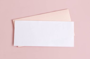 Dikdörtgen boş bir antetli maket ve pembe arka planda bir zarf. Markalaşma ve reklam şablonu