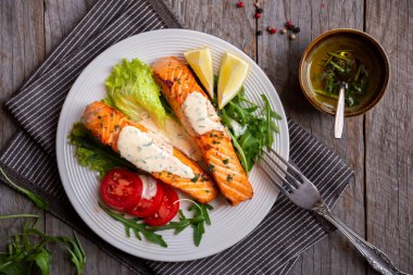 Pişmiş somon balığı fileto, otlar, limon ve sebzeler.