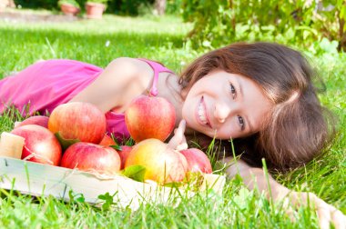 Genç ve güzel bir kız parkta çimlerin üzerinde yatıyor.