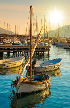 Deniz kıyısında gün batımı ve tekneler