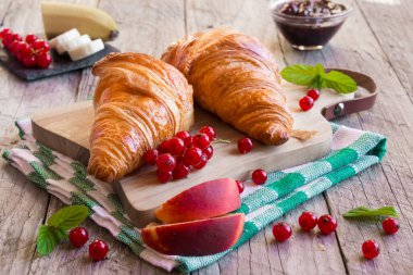 Böğürtlenli taze kruvasan ve ahşap arka planda kahve.