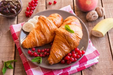 Böğürtlenli taze kruvasan ve ahşap masada kahve.