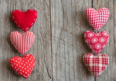 Ahşap arka planda kalp şeklinde kırmızı yastıklar