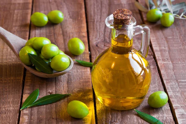 olive oil and green olives on wooden background