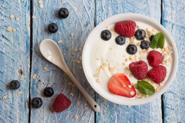 Ahşap arka planda taze böğürtlenli yoğurt.