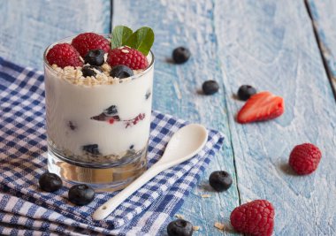 Ahşap arka planda böğürtlen ve yabanmersinli ev yapımı yoğurt. seçici odak.