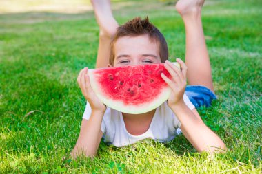 Parkta karpuz yiyen kızıl saçlı şirin bir çocuk.