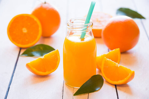 orange juice and oranges on wooden background