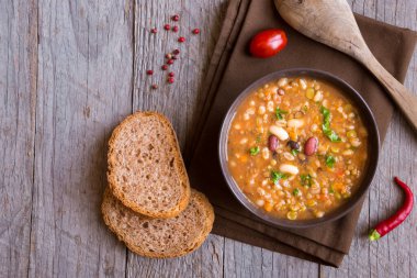 Sebzeli mercimek çorbası ve ahşap zemin üzerinde kızarmış ekmek.