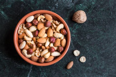 Koyu bir arka planda ahşap bir kasede fındık karışımı. en üstteki görünüm.