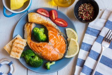 Limonlu ızgara somon bifteği ve ahşap arka planda sebze.