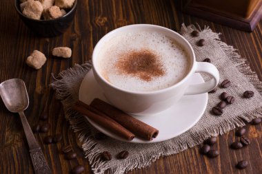 Bir fincan tarçınlı kahve ve ahşap arka planda anason.