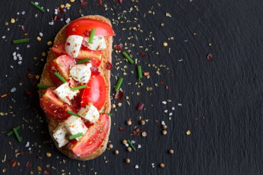 Domatesli bruschetta, mozzarella, siyah arka planda zeytinyağı ve fesleğen. en üstteki görünüm.