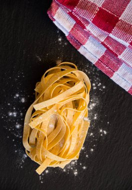 Siyah arka planda ahşap bir kasede çiğ makarna.