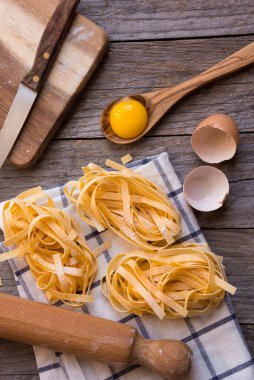 Ahşap zemin üzerinde malzemeler olan çiğ ev yapımı makarna.