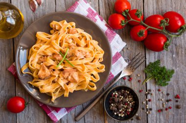 domates soslu makarna ve ahşap masada fesleğen yaprakları.