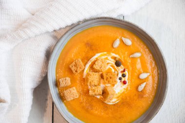 Kabak çorbası ve beyaz ahşap arka planda kızarmış ekmek.